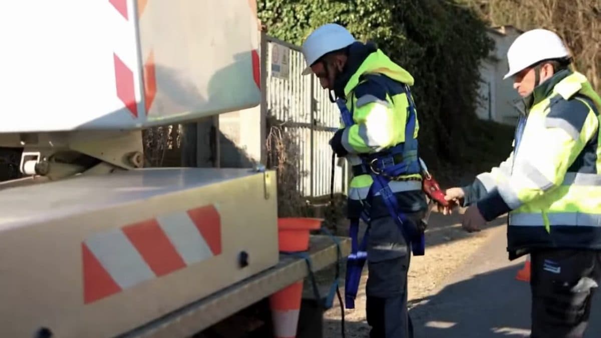 Deux techniciens équipant leur harnais devant un camion nacelle de chantier